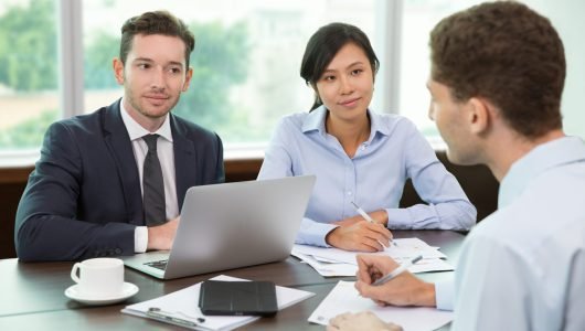 Group of business people holding meeting in office. Two business people listening to their colleague. Teamwork concept